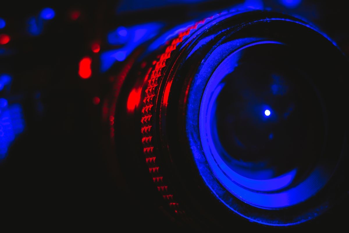 Detail of a professional camera and lens illuminated in red and blue